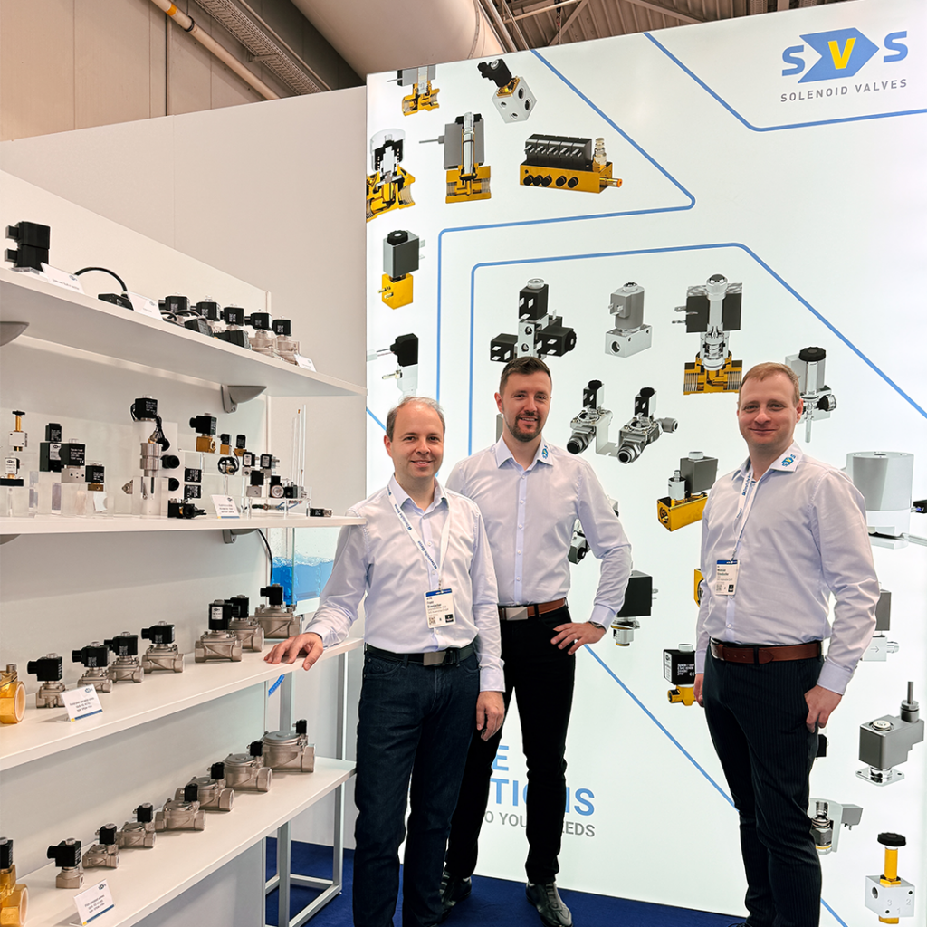 Zu sehen sind die 3 Geschäftsführer von SVS-Automation, wie sie vor ihrem Messestand auf der Hannover Messe posieren.